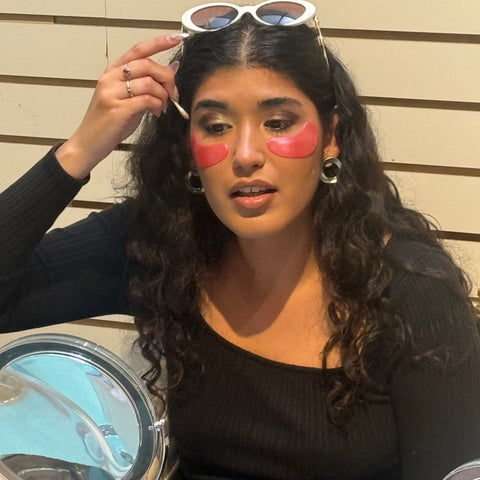 Woman with makeup looking into a compact mirror outdoors
